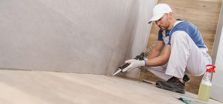 Professionnel effectuant le jointement du carrelage de la douche italienne