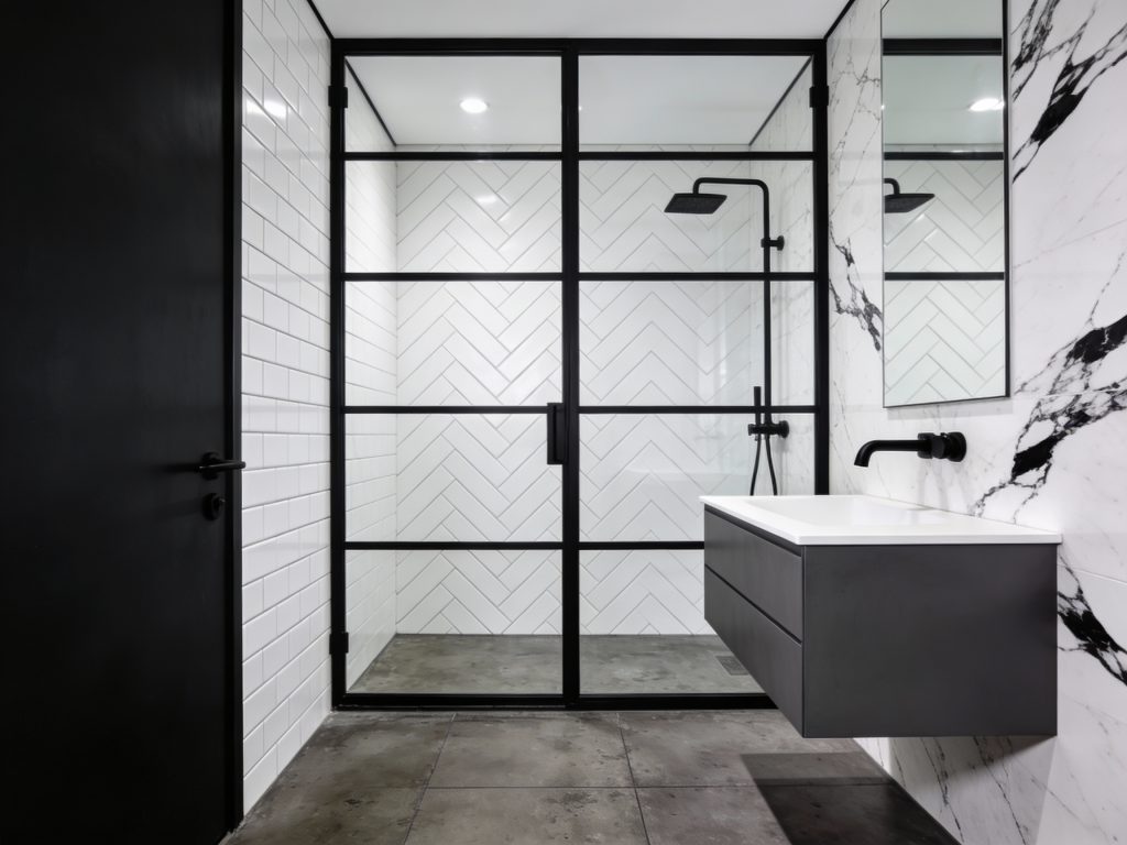 Salle de bain style industriel noir et blanc avec grande verrière d'atelier douche et mur en marbre blanc veiné noir